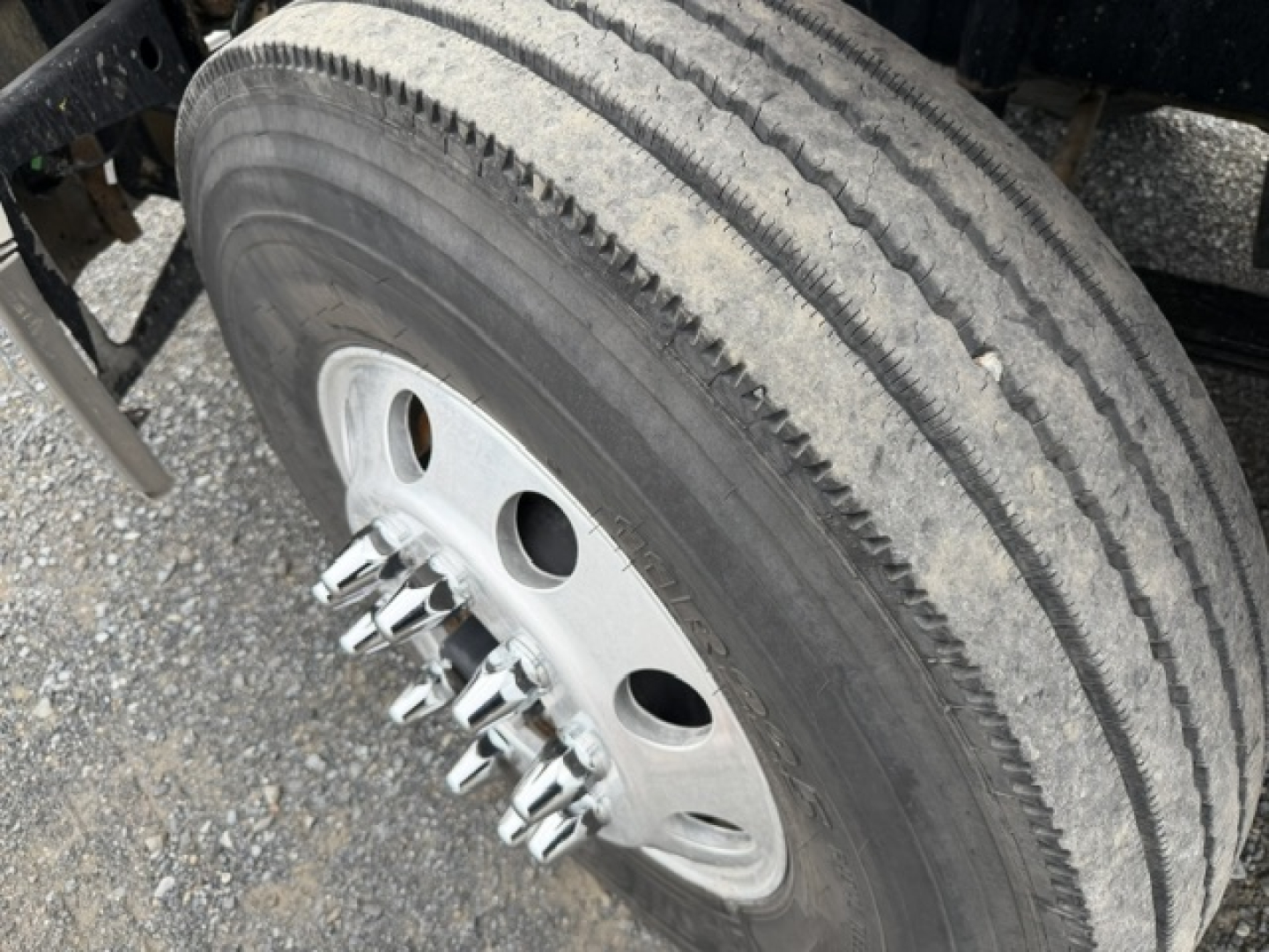 Wheel and tire close-up on Freightliner Cascadia truck showing aluminum threaded lug nuts and tire tread.