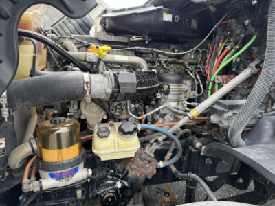 Engine bay of a 2017 Freightliner Cascadia CA125DC showing coolant reservoir, fuel filter, hoses, wiring, and turbo/intercooler area.