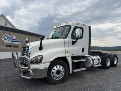 Truck in front of dealership showing a 2017 Freightliner Cascadia CA125DC convention daycab with white cab, dual rear axles, and chrome bumper.