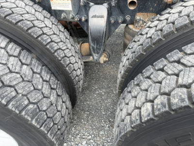 Freightliner Cascadia (CA125DC) undercarriage showing dual rear axles and tire tread, with hitch and chassis components visible.