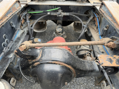 Drivetrain center section of Freightliner Cascadia shows rear differential housing and drive shaft with surrounding frame and hoses (view from under cab).