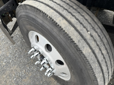Wheel and tire close-up on Freightliner Cascadia truck showing aluminum threaded lug nuts and tire tread.