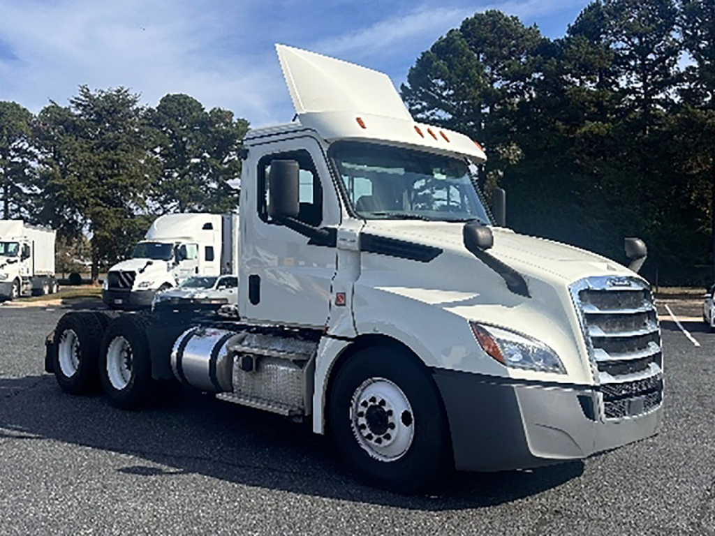 Truck image: white 2019 Freightliner Cascadia126 daycab, front three-quarter view, with sleeper roof fairing raised; VIN badge and stock number visible.