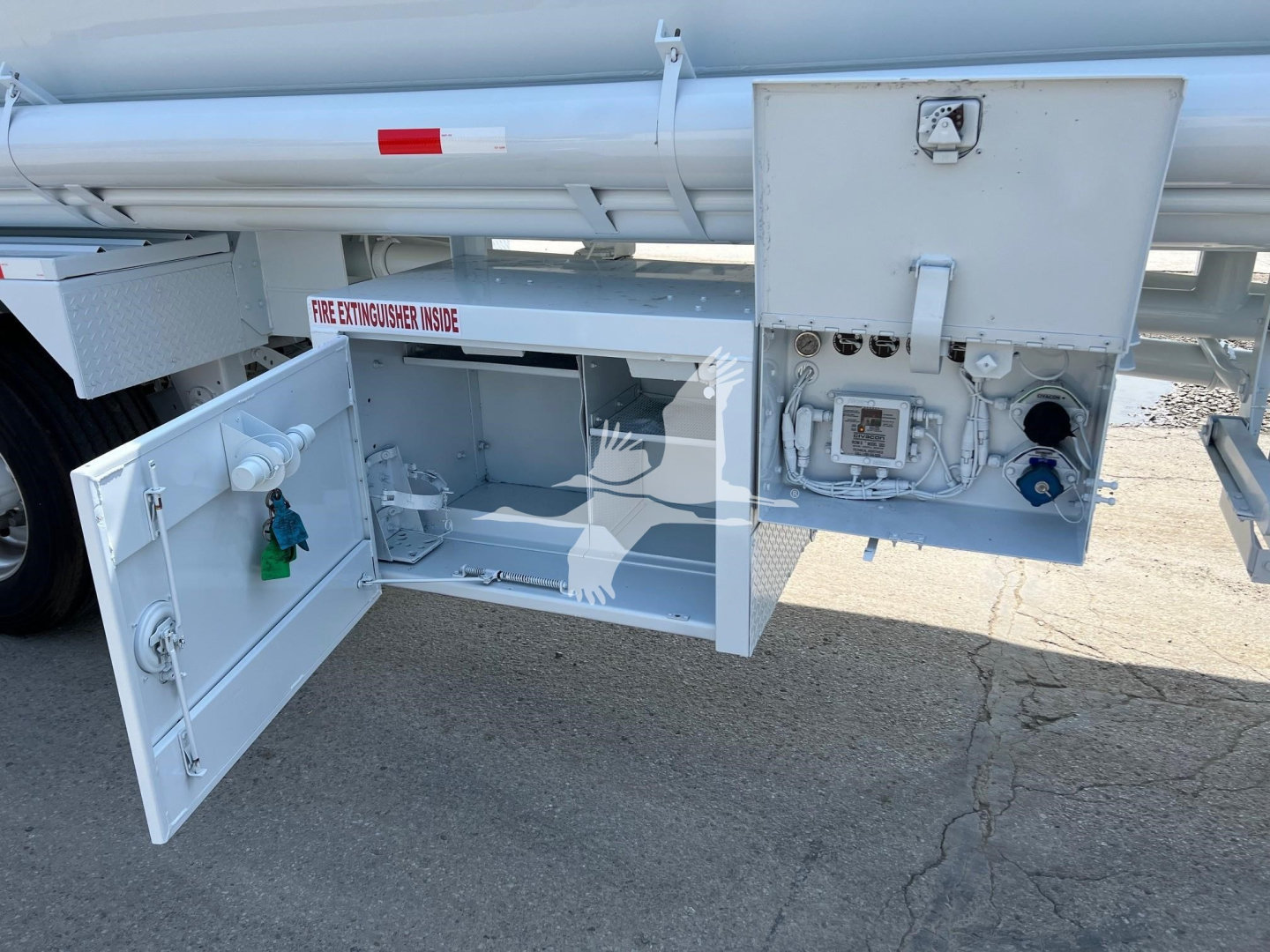 Tank trailer rear panel with maintenance access doors open, showing control box, gauges, hoses, and electrical outlets on the side of a Heil tank trailer.