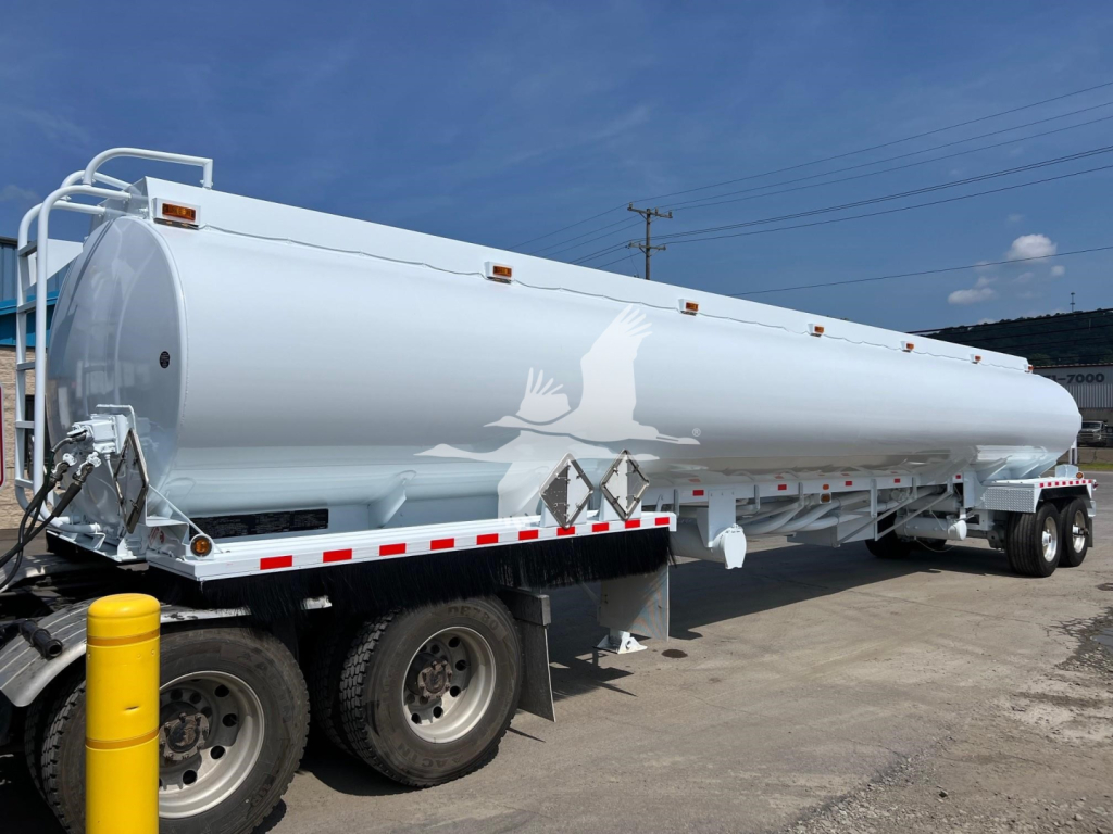 Tank trailer showing large white Heil fuel tanker on a flatbed trailer with wheels and safety rails.
