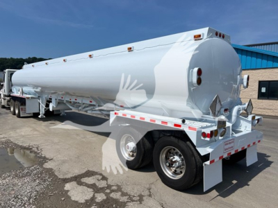 Heil petroleum tank trailer with white cylindrical tank and dual rear axles, rear-end discharge, safety lights, and mounting brackets.
