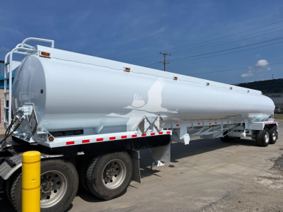 Tank trailer showing large white Heil fuel tanker on a flatbed trailer with wheels and safety rails.