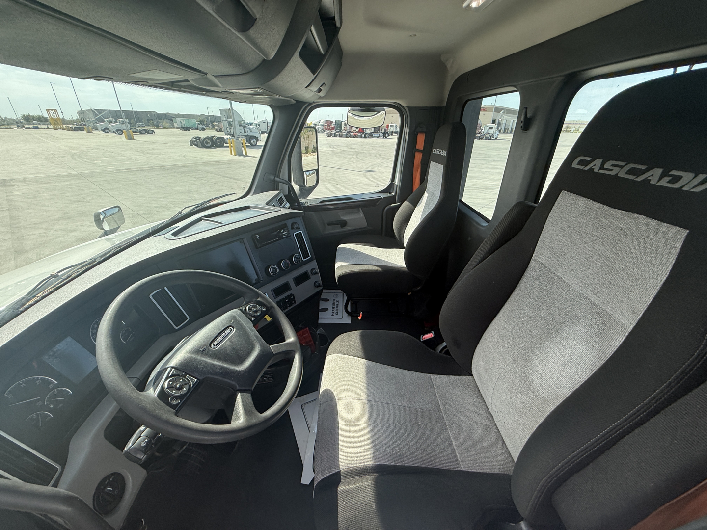 Cab interior of a 2021 Freightliner PT126064S T truck showing steering wheel, dashboard, and Casca... seats with two-tone fabric.