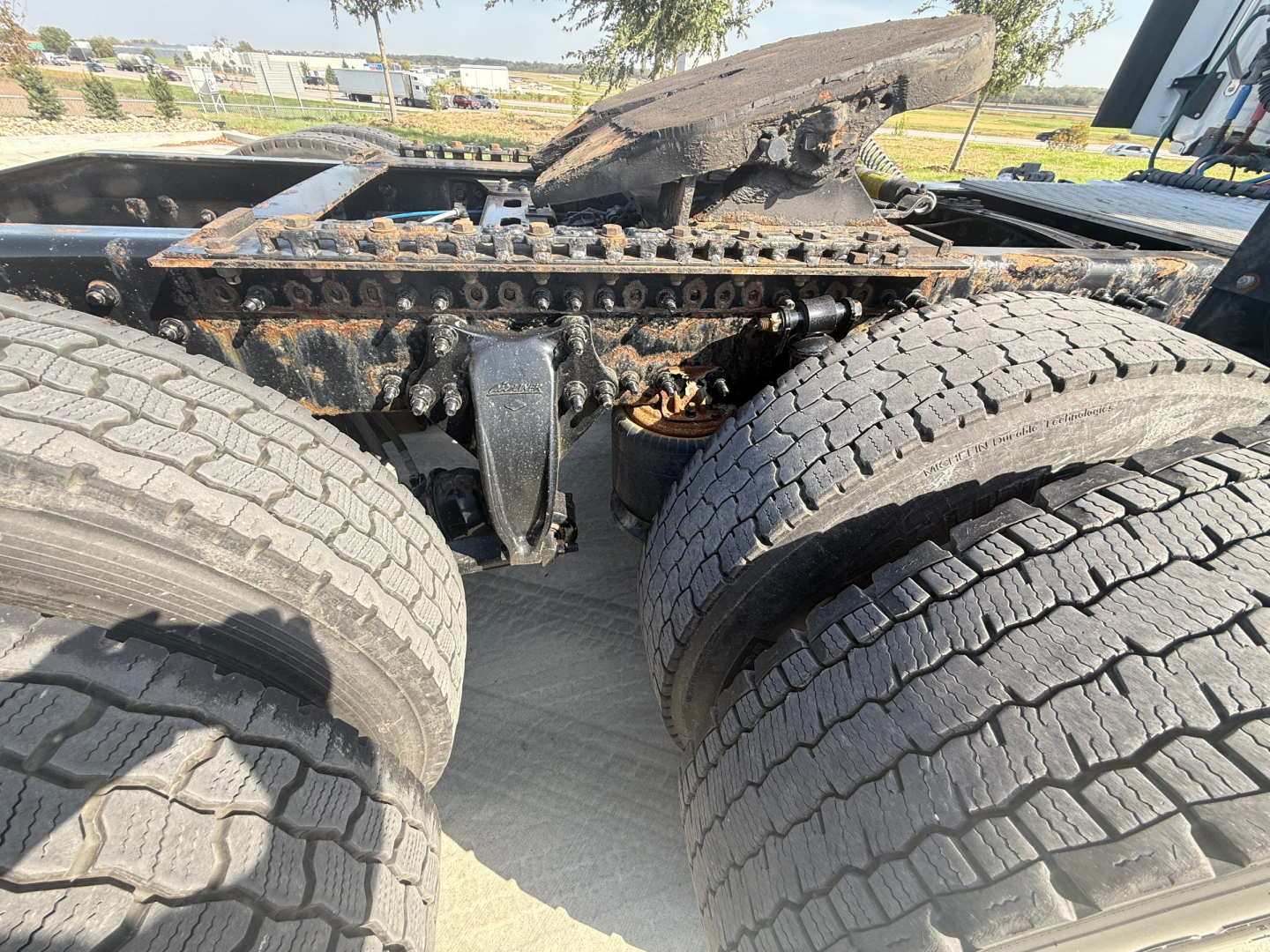 Trailer chassis view showing dual rear axles and truck frame with damaged fifth wheel mounting