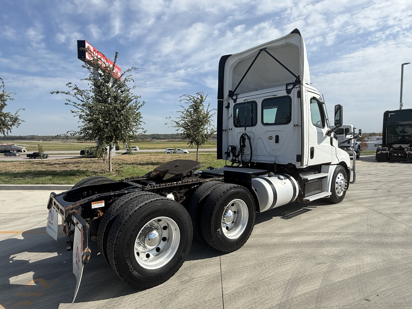 Truck chassis and cab of a Freightliner PT126064S T tractor. Rear view shows dual rear axles, fifth wheel area, exposed fuel tanks, and white cab with open sleeper area.