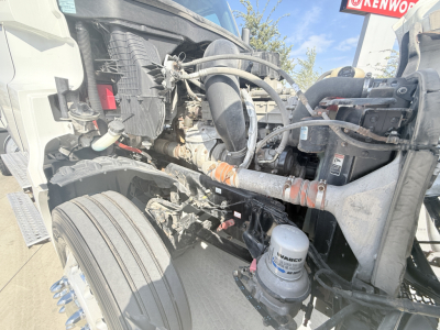 Truck engine bay of a Freightliner PT126064S T showin g engine components, hoses, and a WASHER bottle; front section with frame rails and air intake visible.