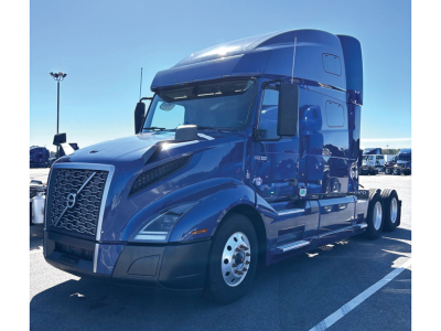 Blue Volvo VNL 760 semi-truck tractor in a parking lot, front-left view, with chrome grille and large aerodynamic cab