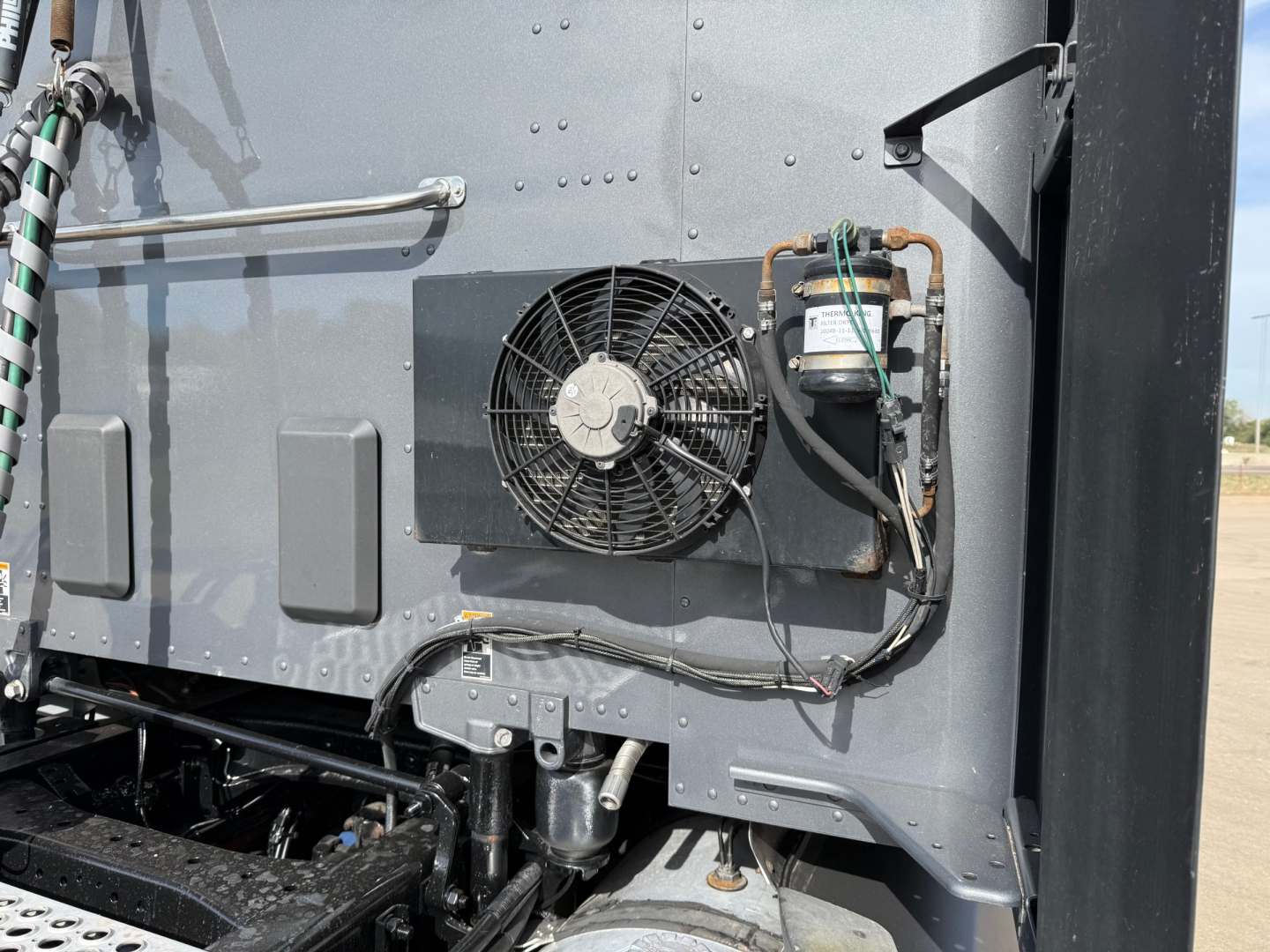 Kenworth T680 rear engine bay with radiator cooling fan and condenser visible, mounted on gray cab panel.