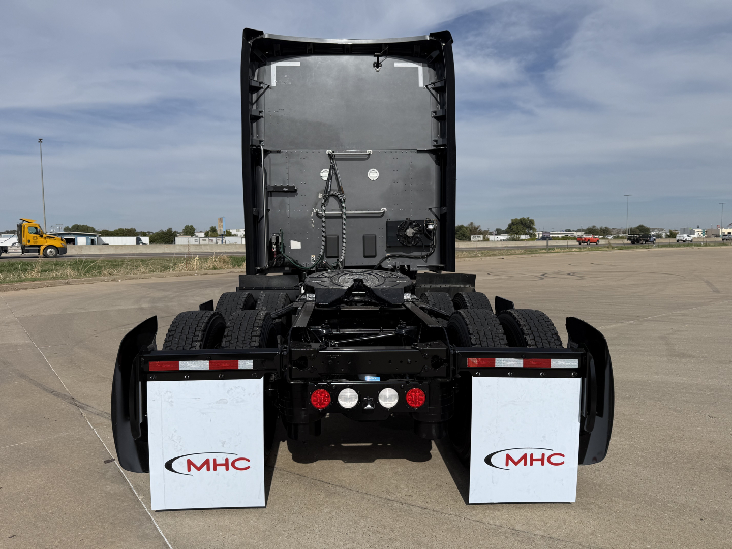 Kenworth truck rear view showing fifth wheel and mud flaps with MHC logos.