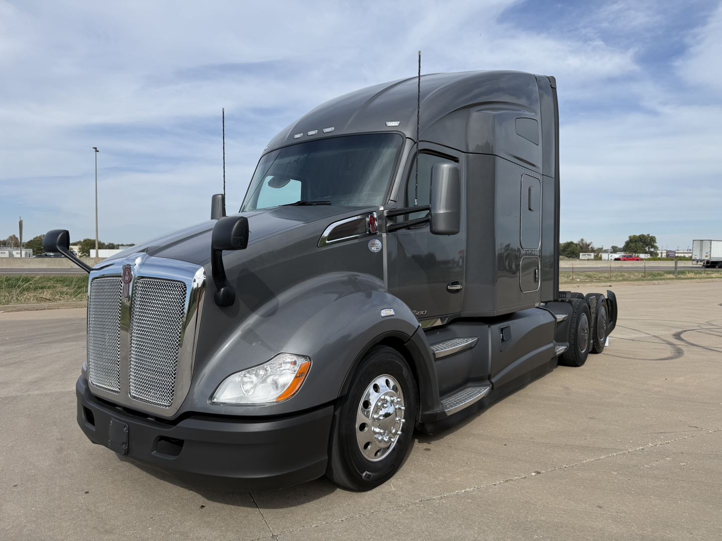 Kenworth T680 in-service tractor with sleeper cab, front grille, and dual rear axles; gray exterior; chrome grille and wheels visible.
