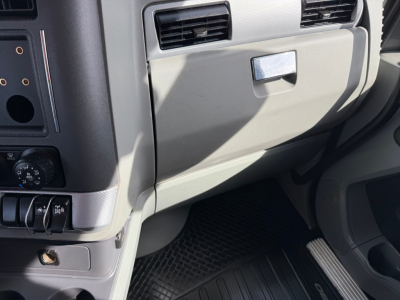 Kenworth T680 dash area showing glove compartment, vent, and floor mat in view.