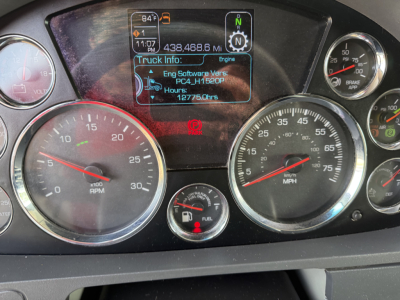 Dashboard of a Kenworth T680 showing gauges and a central digital display with truck info. Visible text includes 'Engine Software Varies', 'PC4H_1520P', 'Hours', '12775.0hrs', and mileage '438,468.6 Mi'. Also gauge labels for RPM and speed 