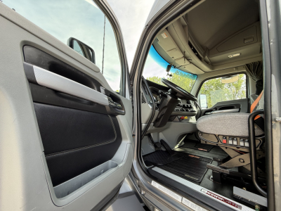 Kenworth T680 truck interior view of the cab with open door showing steering wheel and driver seat area.
