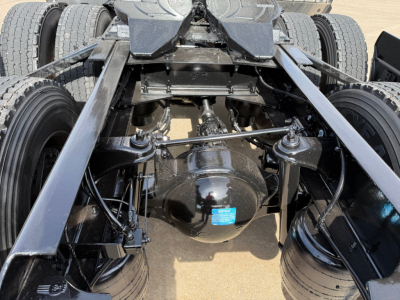 Rear view of Kenworth T680 chassis showing rear axle differential, suspension links, and dual rear tires with blue sticker on differential housing.