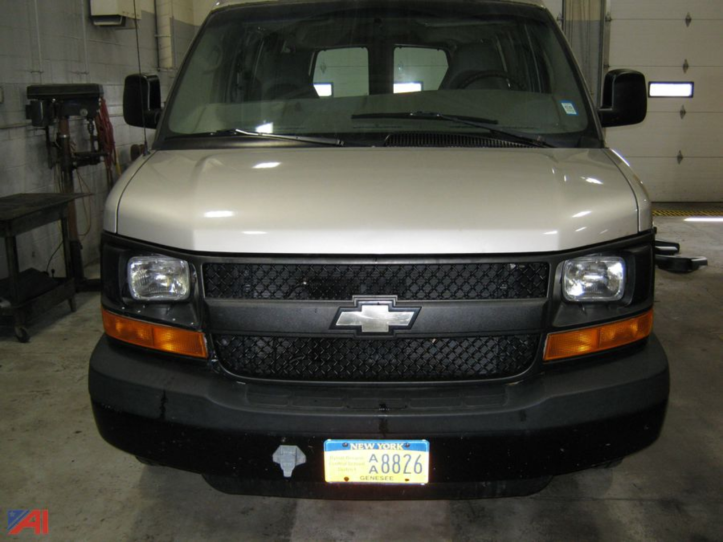Chevrolet Express 1500 cargo van front view in a garage showing grille emblem and New York license plate.