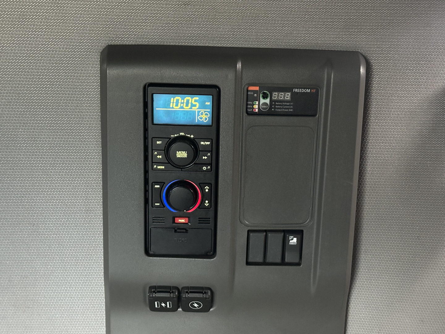 In-cab control panel with digital clock showing 10:05, climate and media controls, and auxiliary panel; part of Volvo truck interior.