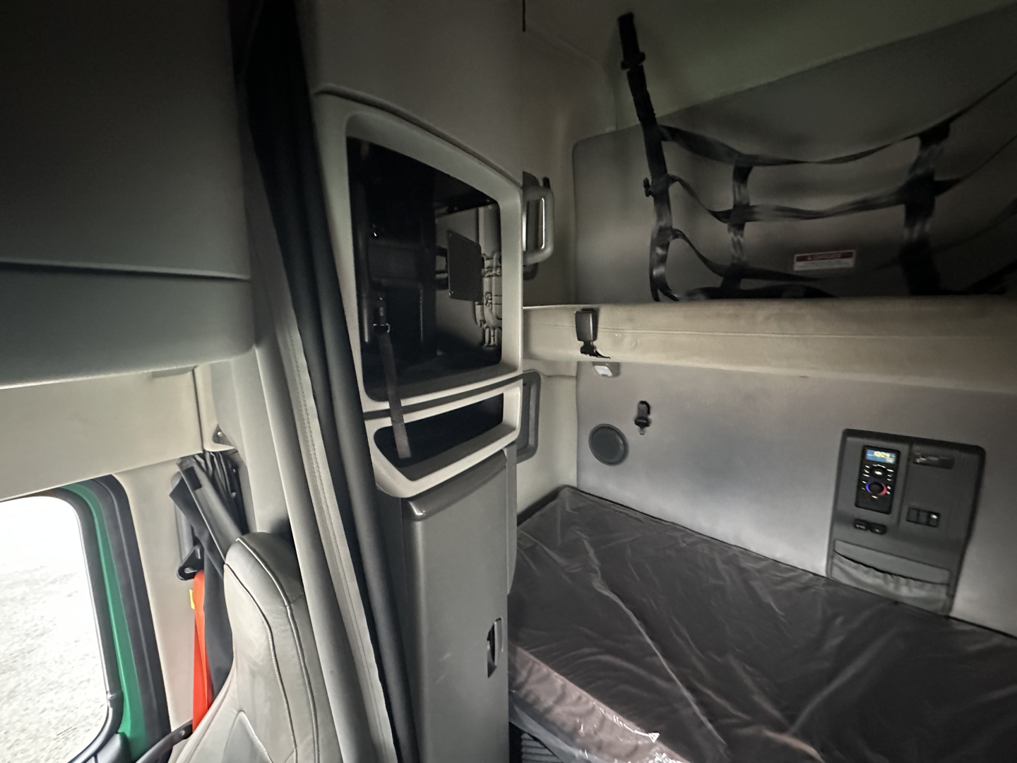 Volvo VNL64T760 sleeper cab interior showing storage cabinet and sleeper bunk area with controls panel.