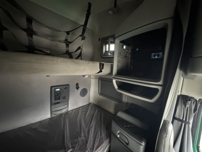 Volvo VNL sleeper cab interior showing storage alcove, control panel, and window with overhead bunk area.