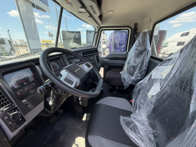 Truck cab interior showing steering wheel, dashboard, and driver seat in plastic.Clearly visible are instrument cluster, center console, and passenger seat wrapped in plastic.