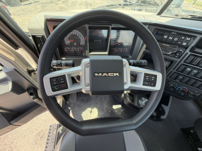 Mack GR64F truck cab interior showing steering wheel with MACK logo, dashboard gauges, and control panels