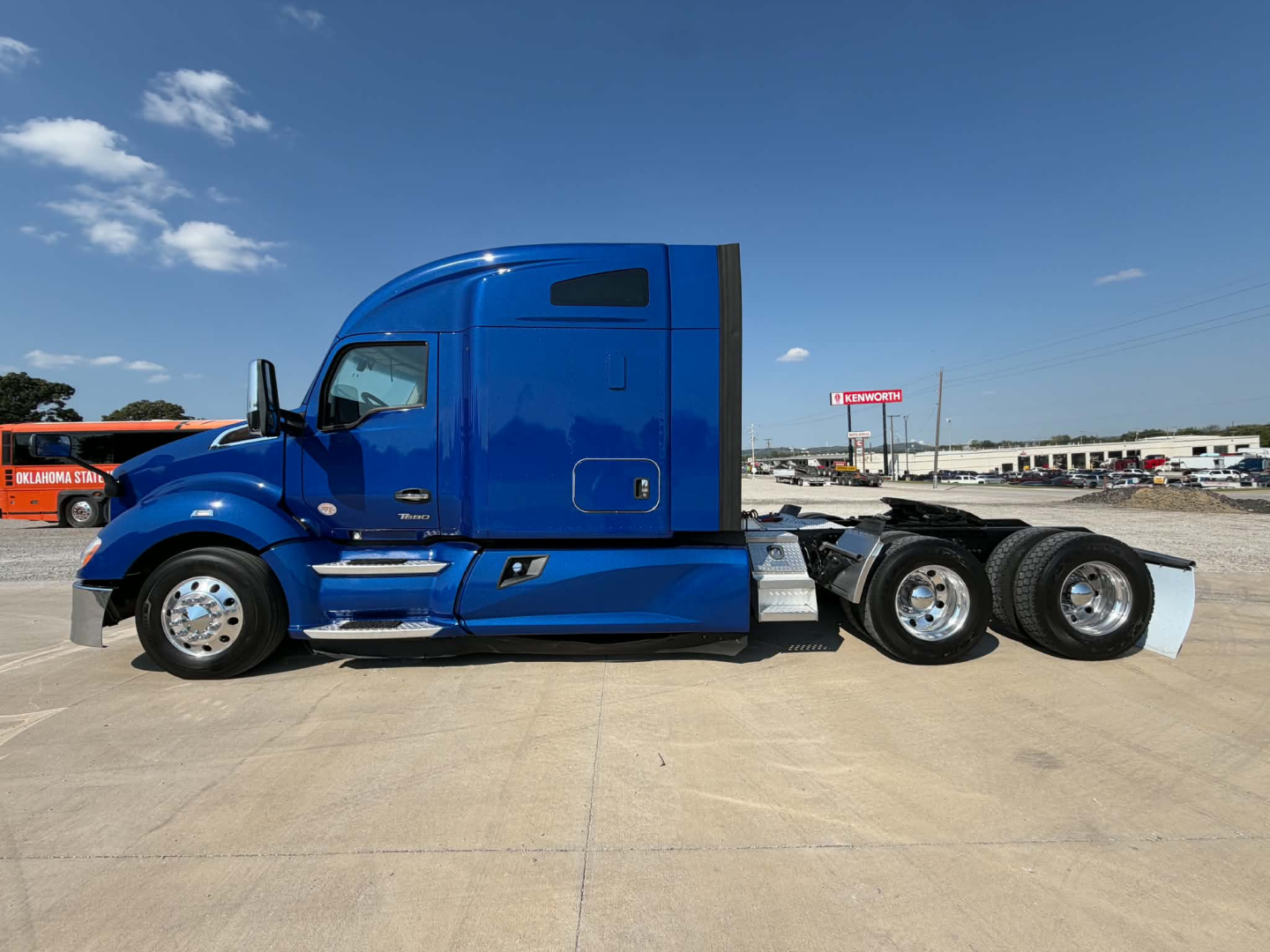 Kenworth T680 conventional sleeper tractor in blue, side view showing cab with aerodynamic design and attached dual rear axles.