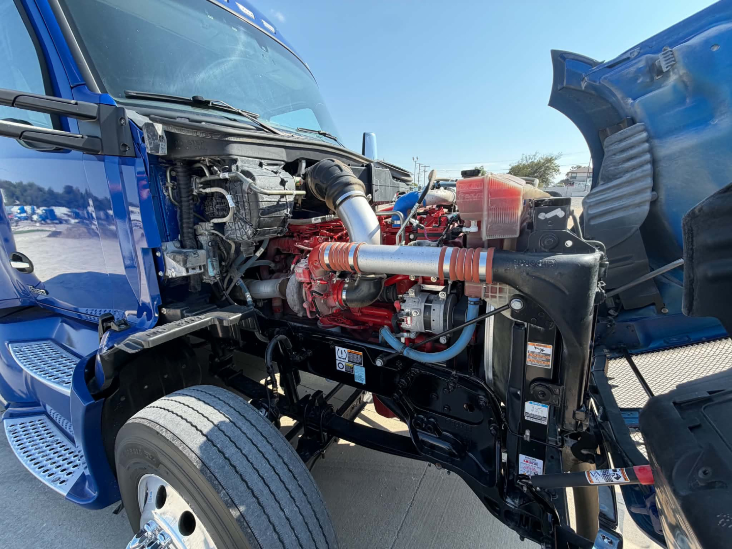 Kenworth T680 engine bay showing diesel engine and surrounding components under open hood.