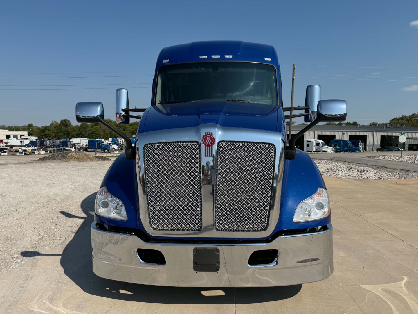 Kenworth T680 front view showing chrome grille, blue cab, side mirrors, and front bumper.