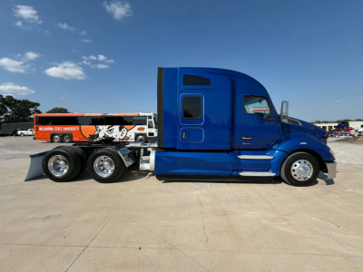 Blue 2022 Kenworth T680 conventional sleeper truck profile with chrome wheels, trailer hitch, and Oklahoma State University graphics on a park lot.