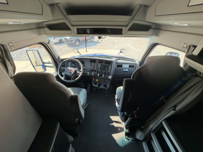 Kenworth T680 truck cab interior showing steering wheel, dashboard, driver and passenger seats, overhead console, and side windows.