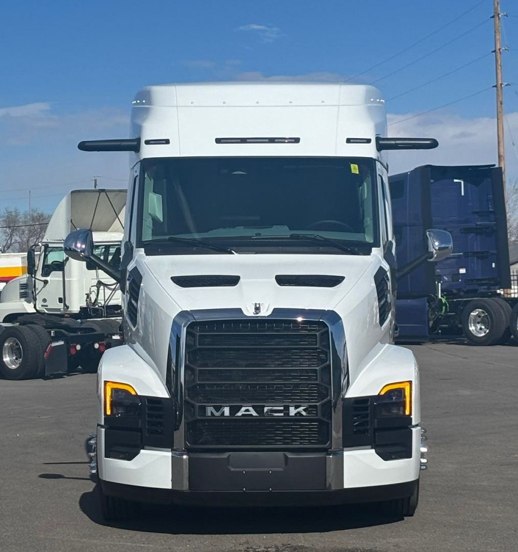 Front view of a white 2026 Mack PR64T76M truck cab with black grille and yellow daytime running lights.