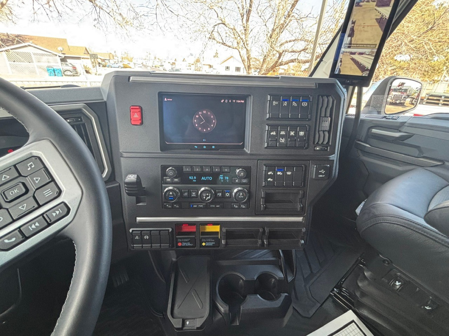Mack truck cab interior showing dashboard with digital gauge display, climate controls, and cupholders in view.