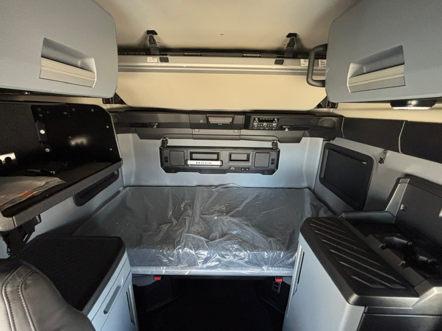 Truck cab interior showing sleeper berth area with storage cabinets, overhead panels, and control console.