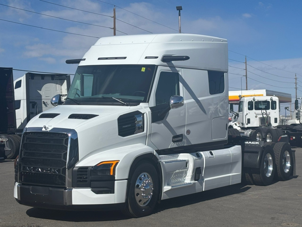 Mack PR64T76M conventional sleeper truck in white side view showing cab, headlights, mirrors, and chrome fuel tanks.