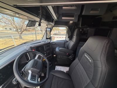 Cab interior of a 2026 Mack PR64T76M showing steering wheel, dash, and driver seat with Mack logo embroidered.