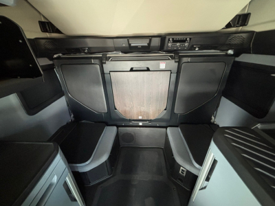 Cab interior of a Mack PR64T76M showing front bunk area with storage cabinets and control panel at top center.
