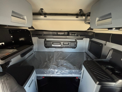Truck cab interior showing sleeper berth area with storage cabinets, overhead panels, and control console.