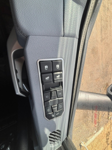 Truck door panel with control switches for windows and mirrors, light gray interior, vertical arrangement of four window controls and lock switches.