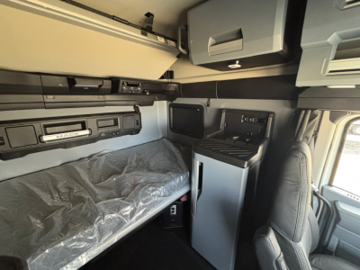 Interior view of a Mack PR64T76M cab showing bunk bed area, overhead storage, and control panels with visible text including 'MACK' and dashboard components.