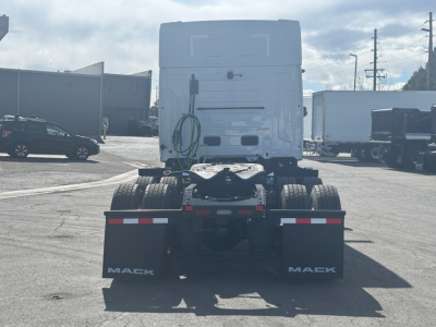 Rear view of a Mack PR64T76M tractor in a dealership lot showing chassis, dual rear wheels, and trailer wiring with MACK mud flaps.