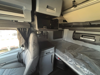 Mack PR64T76M sleeper cab interior showing bunk bed with mattress, storage compartments, and seating area.