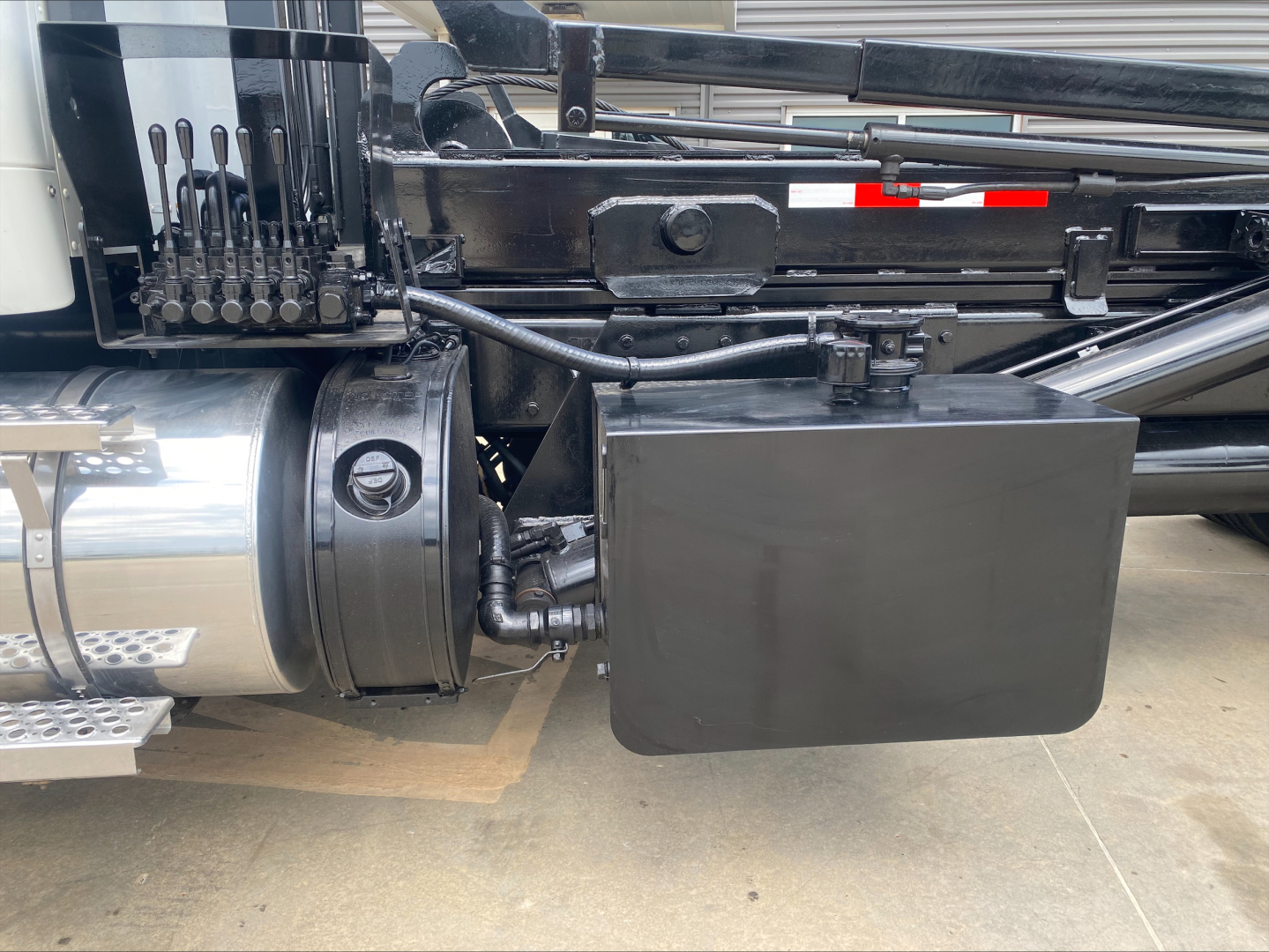 Truck side view showing undercarriage with air tank and hydraulic lines near a black toolbox on a 2019 Kenworth T880.