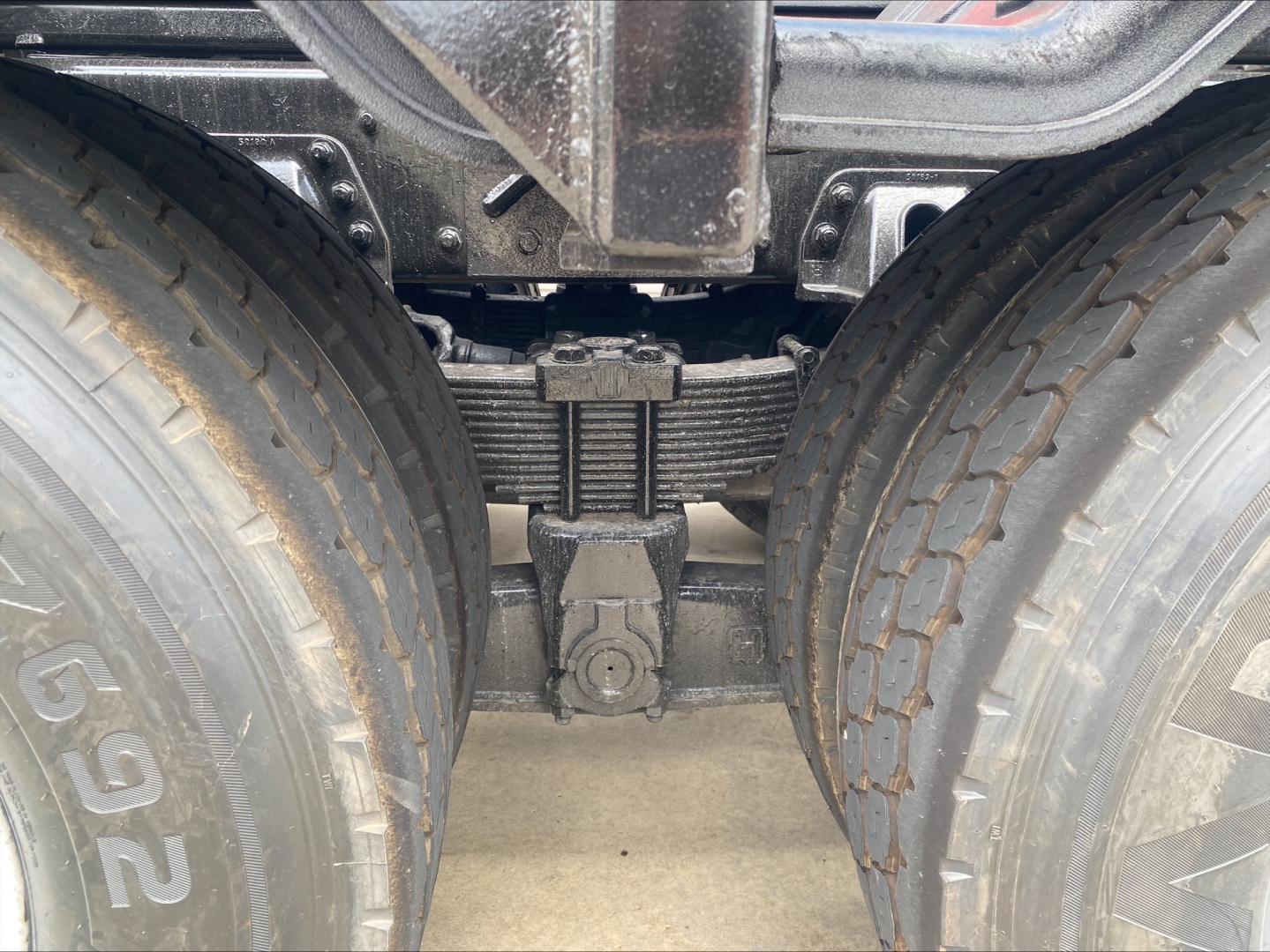 Kenworth T880 axle area showing tandem rear suspension with leaf springs and differential housing between dual tires; view focuses on center axle components