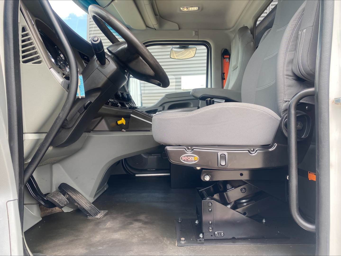 Kenworth T880 cab interior showing driver seat and controls in front of steering wheel.
