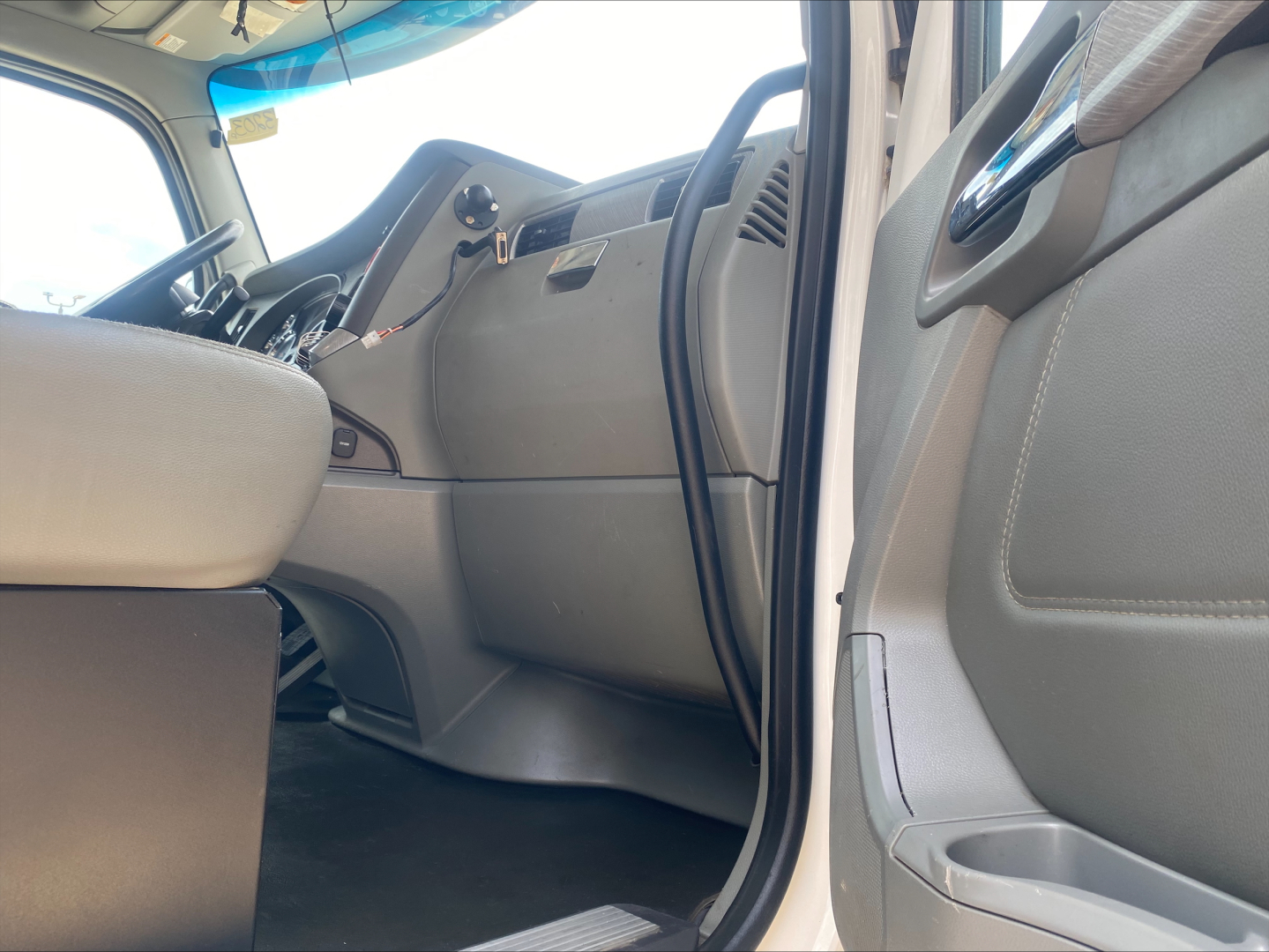 Kenworth T880 cabin interior view from open driver side door showing dash, steering wheel, and front seating area.