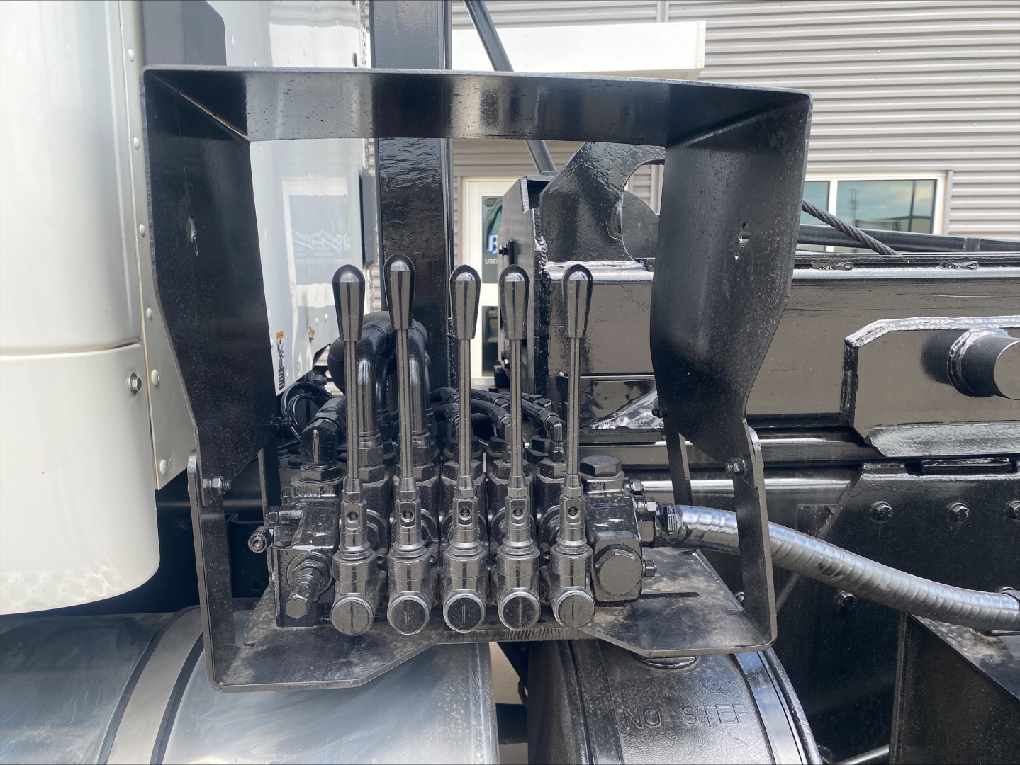 Kenworth T880 engine bay area with multiple hydraulic levers and control valves mounted in a rack.